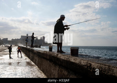 A group of Cuban fishermen silhouetted on the sea wall on the Malecon in Havana Cuba Stock Photo