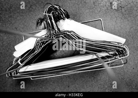 Many several metal wire hangers on pole for hanging clothing in closet storage Stock Photo