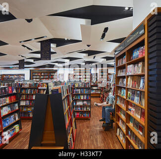 Aisle and reader. Kinokuniya EmQuartier Bangkok, Bangkok, Thailand. Architect: Kay Ngee Tan Architects, 2016. Stock Photo