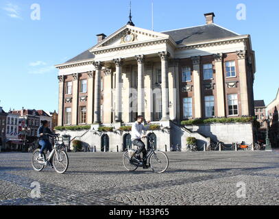 Asian students cycle in front of City Hall (stadhuis) on Grote Markt (Main Square), Groningen, Netherlands Stock Photo