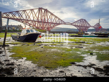 Boat moored in front of the Forth Rail Bridge in Edinburgh, Scotland, connecting the towns of North and South Stock Photo