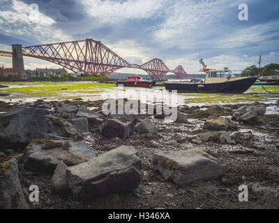 Boat moored in front of the Forth Rail Bridge in Edinburgh, Scotland, connecting the towns of North and South Stock Photo