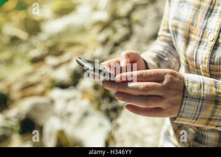 Female tourist using mobile smart phone for GPS navigation in outdoors nature on bright sunny day Stock Photo