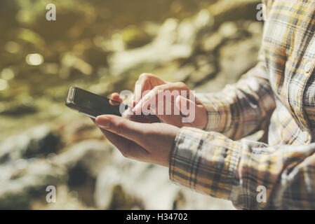 Female tourist using mobile smart phone for GPS navigation in outdoors nature on bright sunny day Stock Photo