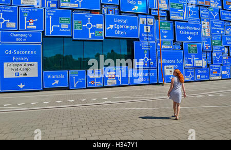 Woman lost her way against a wall with a lot of road signs Stock Photo