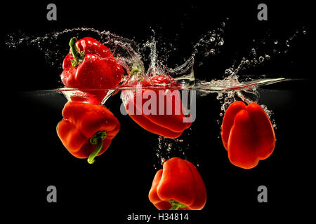 Group of bell pepper falling in water on black Stock Photo