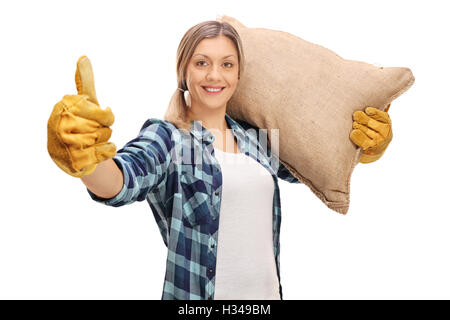Female agricultural worker giving a thumb up and carrying a sack isolated on white background Stock Photo