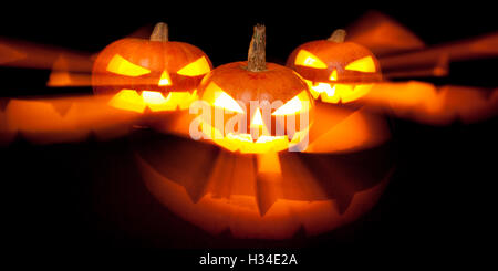 three jack-o-lantern pumpkins glowing in the dark Stock Photo