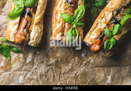 Homemade grilled sausage dogs in baguette on baking paper Stock Photo