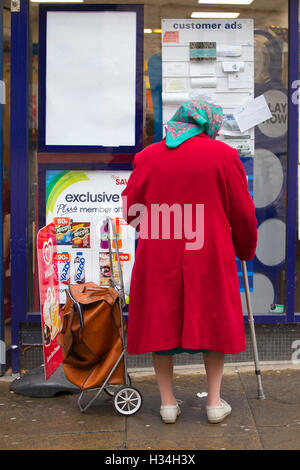 Elderly woman outside newsagent in country town, United Kingdom Stock Photo