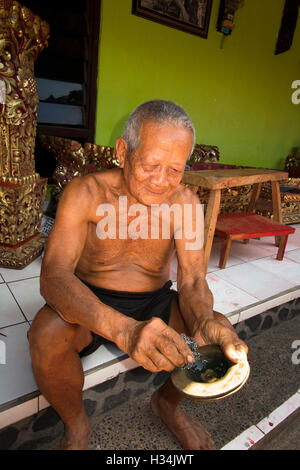 Indonesia, Bali, Lovina, Anturan, old gamelan maker polishing brass gong in village workshop Stock Photo