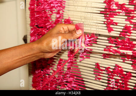 Indonesia, Bali, Singaraja, Pertenunan Berdikari weaving workshop, hands of worker tying plastic dye resist threads Stock Photo