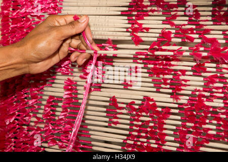 Indonesia, Bali, Singaraja, Pertenunan Berdikari weaving workshop, hands of worker tying dye resist threads Stock Photo