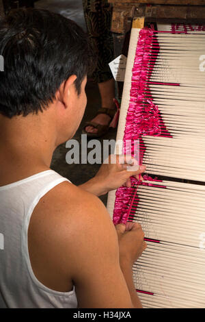 Indonesia, Bali, Singaraja, Pertenunan Berdikari weaving workshop, worker hand tying dye resist threads Stock Photo