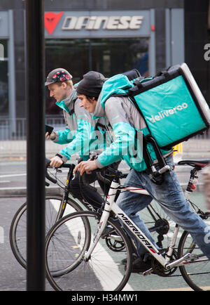 Two cycling couriers for Deliveroo, in Manchester city centre, UK Stock Photo