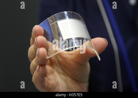 Chiba, Japan. 05th Oct, 2016. An employee at Panasonic holds up the prototype of a bendable lithium ion rechargeable battery at the Ceatec 2016 electronics trade fair in Chiba, Japan, 05 October 2016. The battery could facilitate the development of portable electronics devices in the future, since it can fit flexibly around curvatures. Panasonic will deliver pre-series models to partner companies this fall. The bendable battery will come onto the market in various devices starting in 2018. Photo: CHRISTOPH DERNBACH/dpa/Alamy Live News Stock Photo