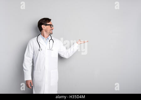 Smiling doctor with stethoscope gesturing Stock Photo