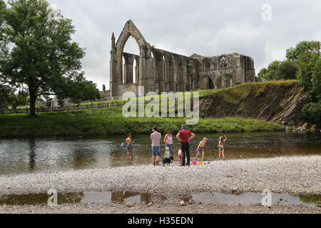 Day trippers enjoy the sunshine and hot temperatures next to the River Wharfe at Bolton Abbey near Skipton in North Yorkshire. Stock Photo