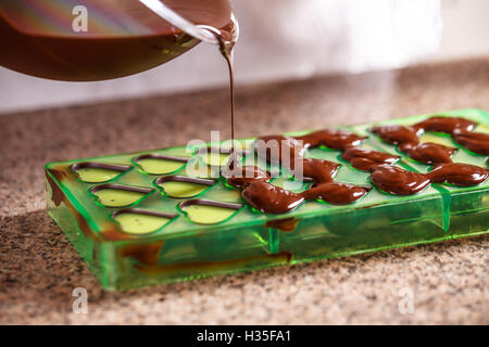 Pouring chocolate in mold, make praline Stock Photo