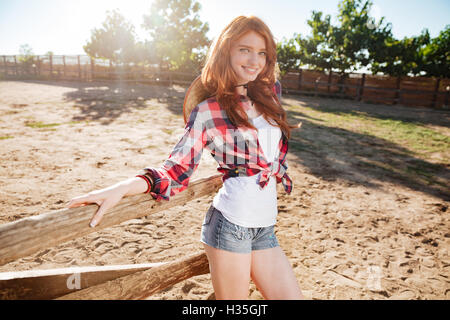 Smiling beautiful young woman cowgirl standing on ranch Stock Photo