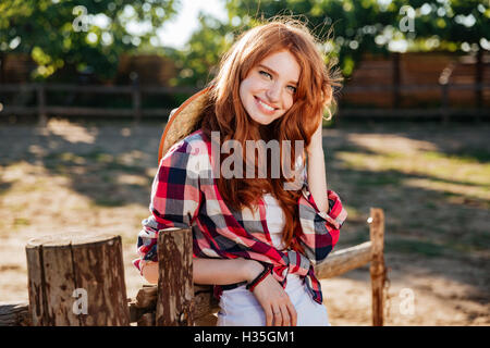 Happy cute young woman cowgirl standing and smiling on farm Stock Photo