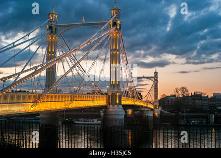 Albert Bridge illuminated at sunset over the river Thames London UK Stock Photo