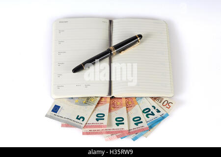 Earning money with writing symbolized with pen and notebook on euro money banknotes Stock Photo