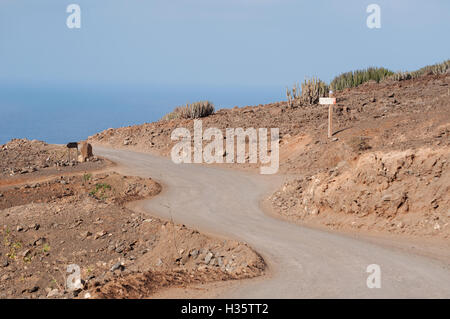 Fuerteventura, Canary Islands, North Africa: dirt road and wooden sign to Cofete, a 30 km beach backed by the most impressive mountains of the island Stock Photo