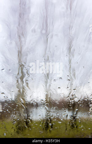 Trees seen through a rain splashed car window. Stock Photo