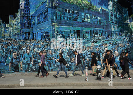 NYC pedestrians walk past a large mural painted by Logan Hicks on the Bowery Mural Wall, Houston Street Stock Photo