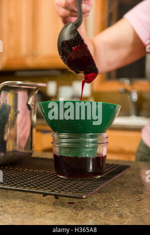 Pouring the grape juice in canning jars to make homemade jelly or jam. Stock Photo