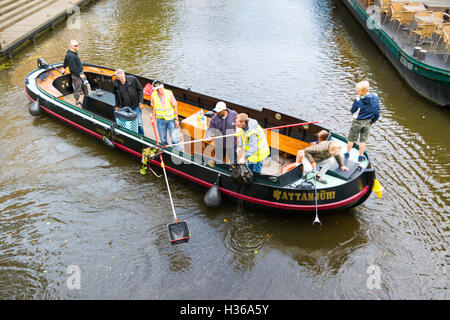 People on boat collecting left waste cleaning canal water from litter in downtown Leiden, Netherlands Stock Photo