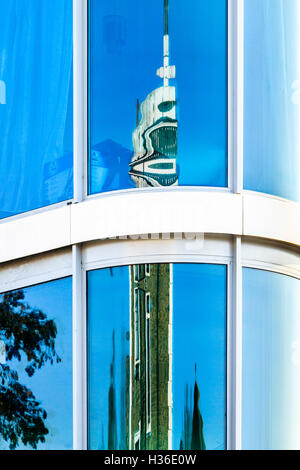 Geometrical composition of brilliant blue sky and tall building reflected in the curved glass façade of a London apartment building Stock Photo