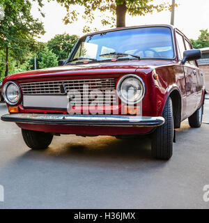 Red vintage retro car parked under tree at sunset Stock Photo