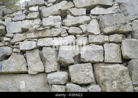 Portland Stone Wall at Tout Quarry, Portland. A small carved face is visible on one of the stones. Stock Photo