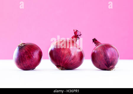 Group of three red onions on violet Stock Photo
