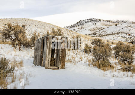 Leaning outhouse with a rusty horseshoe hanging on the corner on a winter day Stock Photo