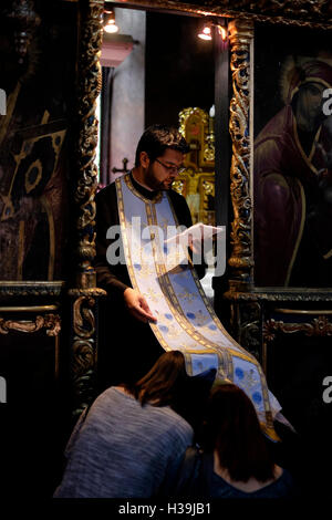 A Romanian Orthodox priest gives blessings to believers inside St. Antony's Orthodox Church, known as the Church of the Annunciation ( Biserica Sfantul Anton ) in the old city of Bucharest, Romania Stock Photo