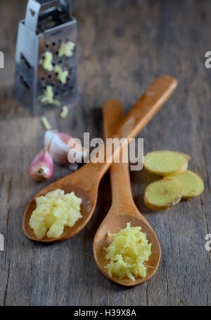garlic and ginger in wooden spoons on wooden table Stock Photo