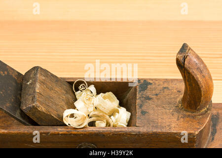 Old carpenter plane and wood shavings on a wooden table Stock Photo