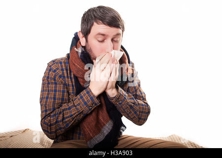 Pale sick man with a flu, sneezing, in a clean background Stock Photo