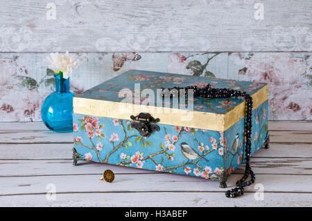 Stunning jewellery chest on a rustic background and decorated with a turquoise vintage paper and gold leaf Stock Photo