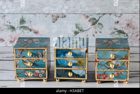 A row of three decoupaged chests of drawers in a vintage floral design and gilded with gold leaf Stock Photo