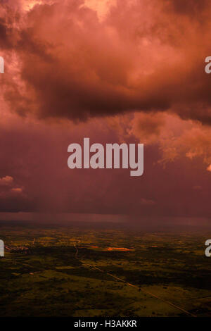 Red stormy and cloudy sky during the sunset through the window of a plane. Stock Photo