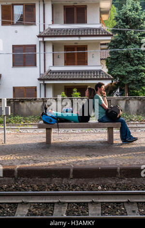 Couple is waiting for their train siting back to back on the end of long holiday day. Stock Photo