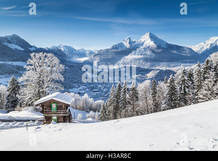 Winter wonderland mountain scenery in the Alps with traditional mountain chalet on a beautiful cold sunny day with blue sky Stock Photo