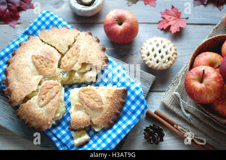 Sliced apple pie with fruit ingredients and cinammon sticks on one side Stock Photo