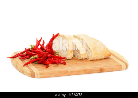 Close view of hot pepper and sliced bread lying on cutting board isolated over white background Stock Photo