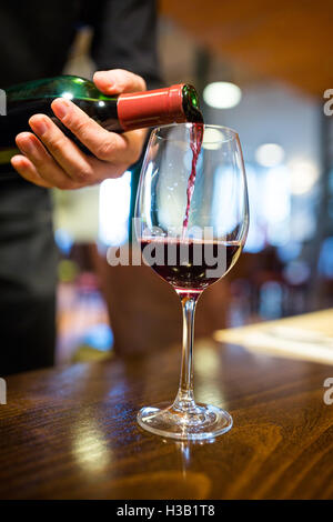 Waiter pouring red wine into glass Stock Photo