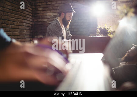 Close-up of customer typing on laptop against man at cafe Stock Photo